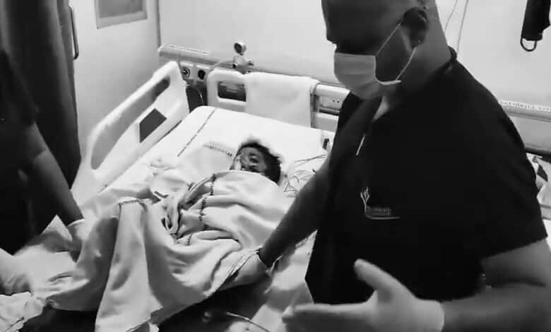 A young boy lying in hospital bed after dog attack in Hyderabad, with medical staff attending to him.