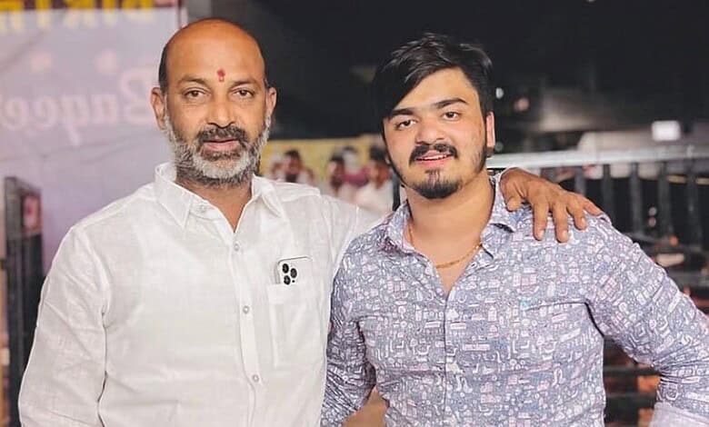 A young man and an older man standing together, smiling, with the older man’s arm around the young man’s.