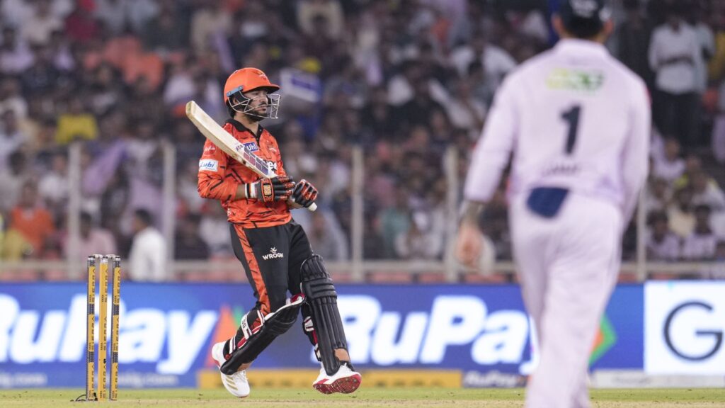 A cricket player in orange uniform celebrating on the field during a match.