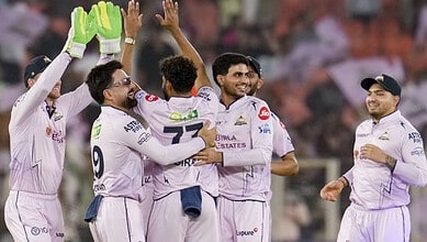 Celebrating cricket victory, Indian team players in white uniforms joyfully embrace on the field.