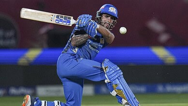 A cricket player in blue uniform hitting the ball with a bat during a match.