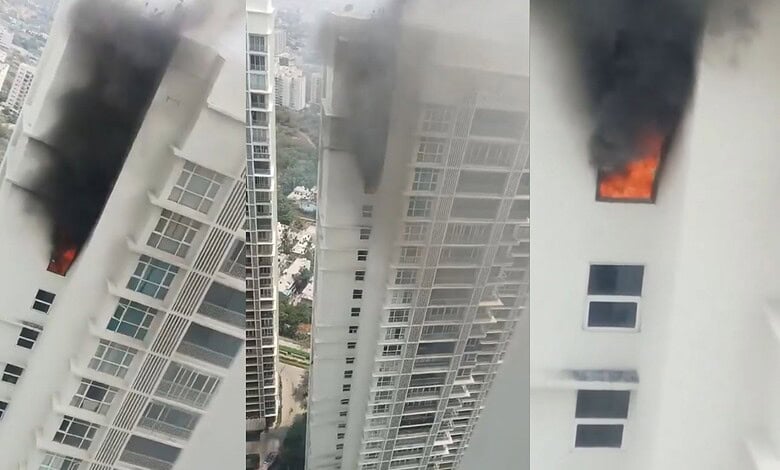 Fire and smoke emerging from a high-rise building window during a daytime fire incident.