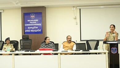 Police commissioner addressing a meeting at Malkajgiri Police Station, with officers seated at the table.
