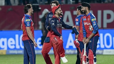 Celebrating cricket players on the field during a match, wearing team uniforms and engaging in team spiri.