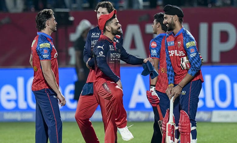 Celebrating cricket players on the field during a match, wearing team uniforms and engaging in team spiri.