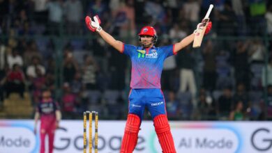 A cricket player celebrating with arms raised on the field during a match.