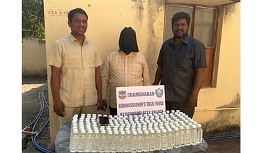 A woman with her face covered standing between two men behind a table with numerous bottles of hand sanit.