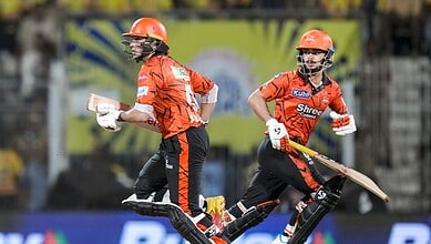 A cricket players in orange uniforms running on the field during a match.