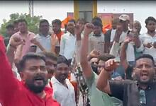 Protesters protesting passionately with raised fists and shouting during a demonstration in an urban area.