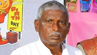 A man with grey hair and a serious expression, celebrating a birthday with colourful decorations and a "H.
