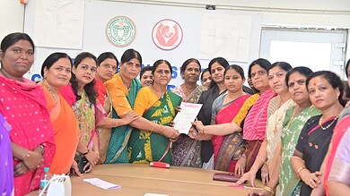 Women in colorful traditional attire participating in a formal meeting or award ceremony in an office set.