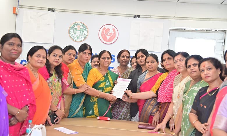 Women in colorful traditional attire participating in a formal meeting or award ceremony in an office set.