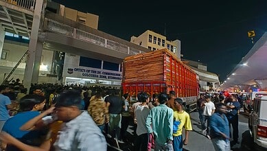 Crowd gathered around a container truck carrying cardboard outside the DCP Golconda Zone office in Hyderabad following stone pelting at Gudimalkapur.