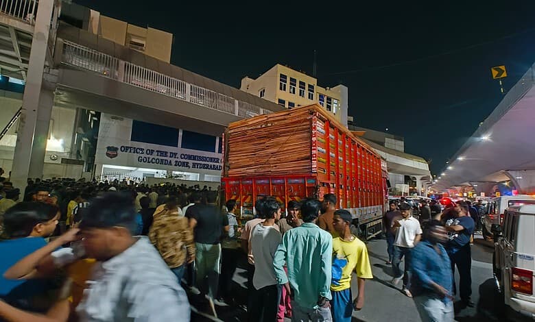 Crowd gathered around a container truck carrying cardboard outside the DCP Golconda Zone office in Hyderabad following stone pelting at Gudimalkapur.