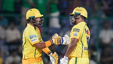 Two cricket players in yellow uniforms exchanging a fist bump during a match.