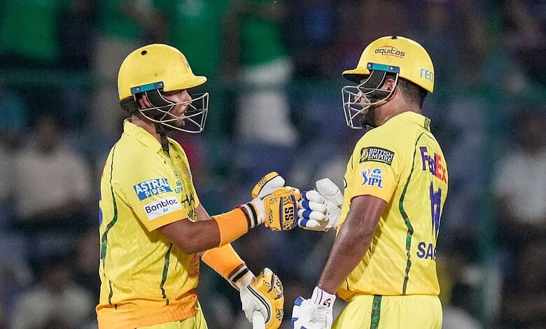 Two cricket players in yellow uniforms exchanging a fist bump during a match.