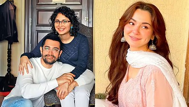 Hania Aamir smiling with a man, both dressed casually, in a cozy indoor setting.