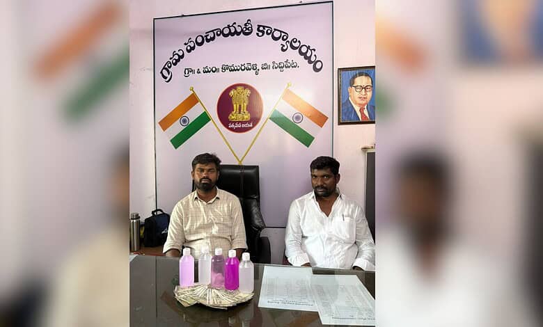 Indian political leaders seated at a desk with national flags and a banner in the background.