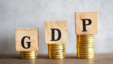 Wooden blocks with letters G, D, P on stacked coins representing economic growth and oil price effects.