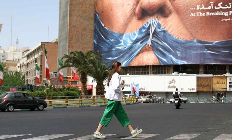 Protesters cover their mouths with a blue cloth in a busy city street amid US-Iran tensions over Hormuz.