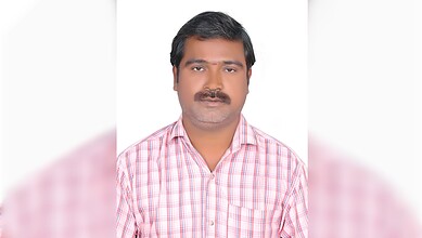 Man in pink checkered shirt looking at camera, professional portrait for Siasat Daily news website.