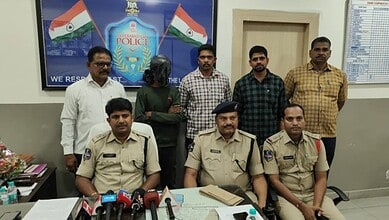 Police officials seated at a table with microphones, surrounded by colleagues in an office setting.