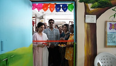 Image shows a woman cutting a ribbon during an event at the Siasat Daily office, with attendees and colourful decorations in the background.