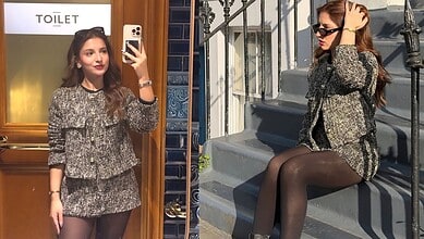 A woman taking a mirror selfie in a stylish mini skirt and blazer outfit, with a "TOILET" sign visible in.