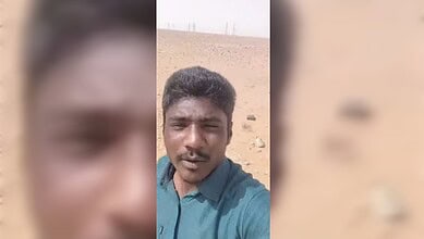 Man standing in a barren desert landscape under a clear sky.