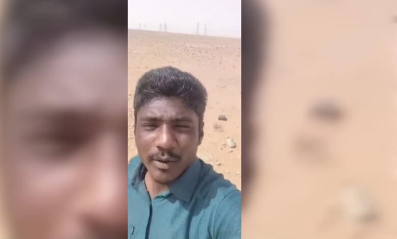 Man standing in a barren desert landscape under a clear sky.