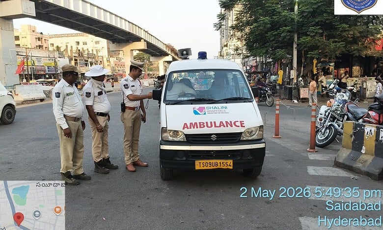 Police officers inspecting an ambulance at a busy intersection in Hyderabad.