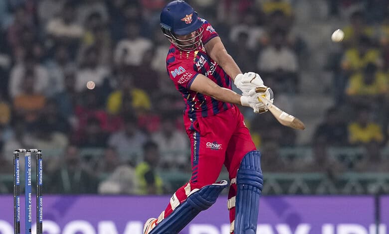 A young cricket player in red and blue uniform hitting the ball during a match.