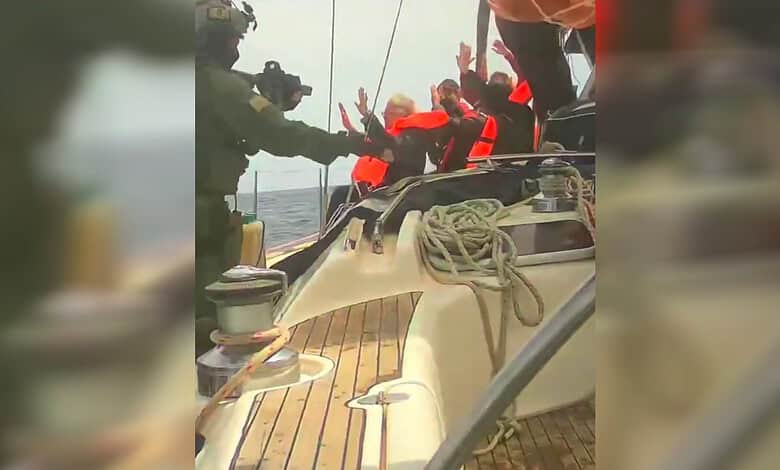 Yacht crew helping passengers with safety gear on a boat at sea.