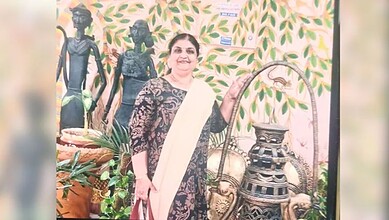 Traditional Indian woman with cultural artifacts and greenery background.