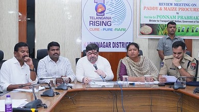 Enhanced image of officials at a meeting discussing Telangana Rising initiatives, with banners in the bac.