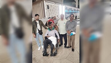 Indian man in wheelchair with family at airport, returning home after stroke treatment in Saudi Arabia.