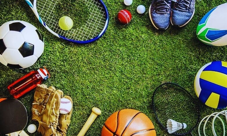 Sports equipment and gear on a grassy field for various sports activities.