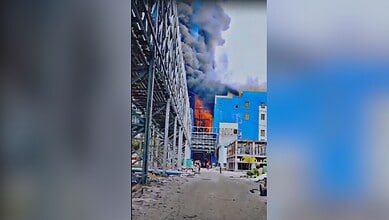 Building fire with thick black smoke and flames in an urban area. Emergency response needed as the struct.