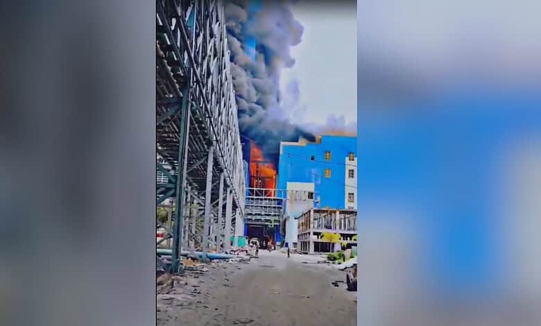 Building fire with thick black smoke and flames in an urban area. Emergency response needed as the struct.