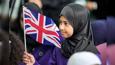 Young Muslim girl holding a British flag during a community gathering in the UK.
