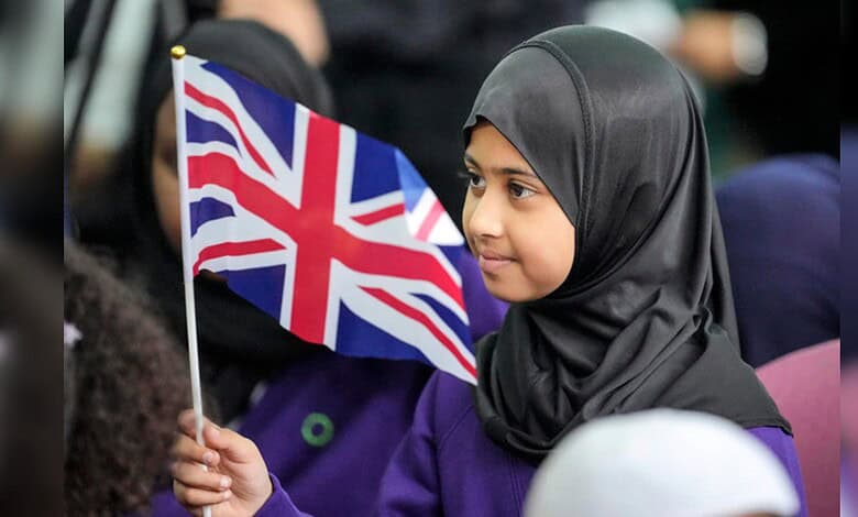 Young Muslim girl holding a British flag during a community gathering in the UK.